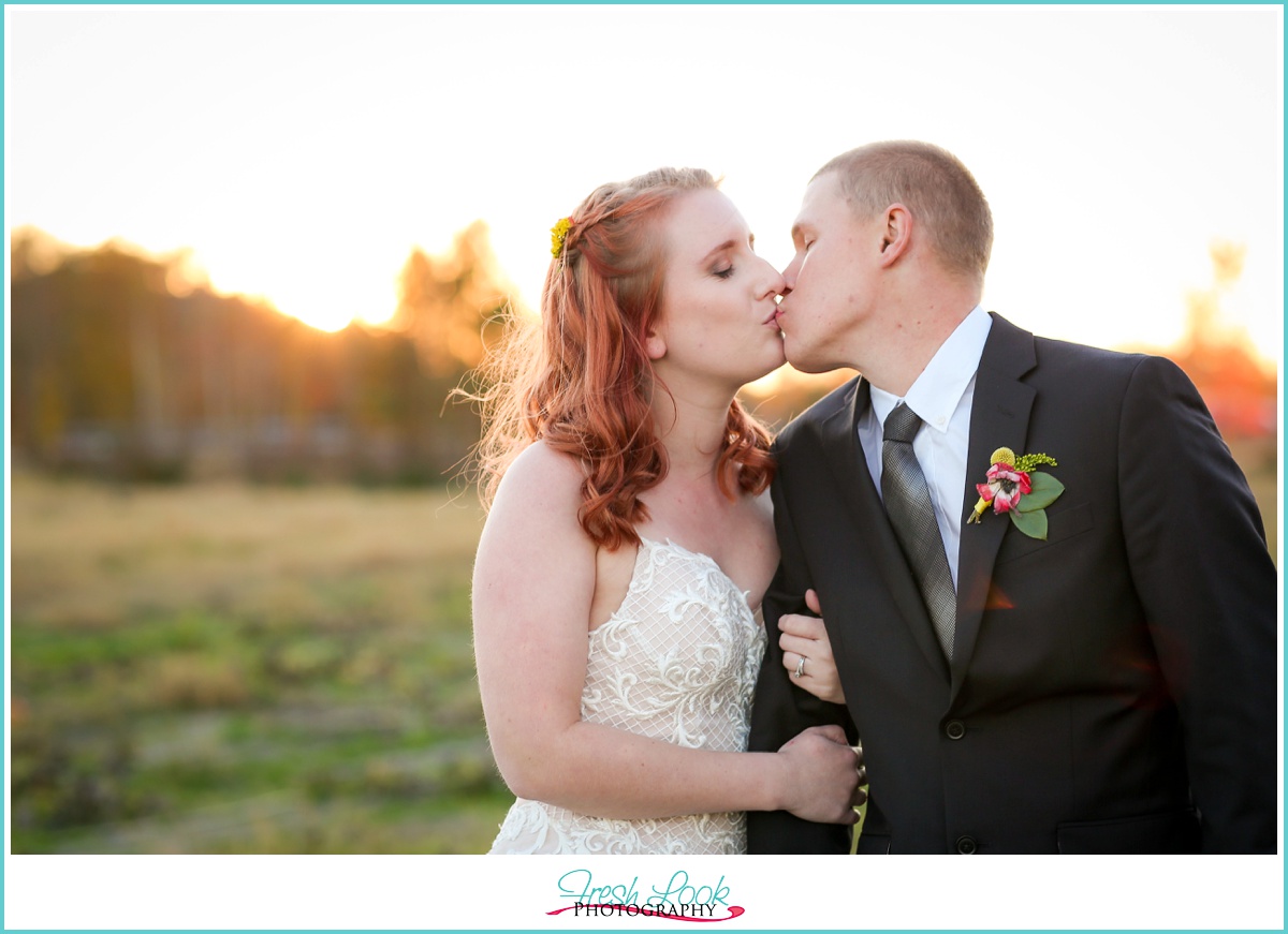 bride and groom kissing at sunset