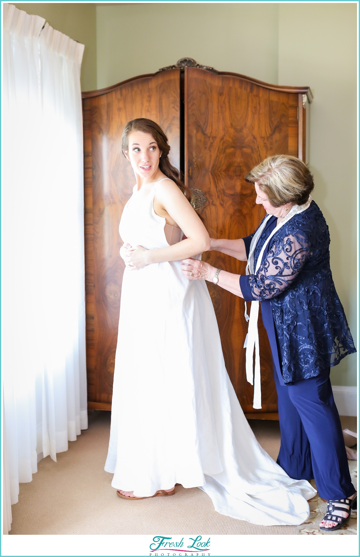 mom helping bride with wedding dress