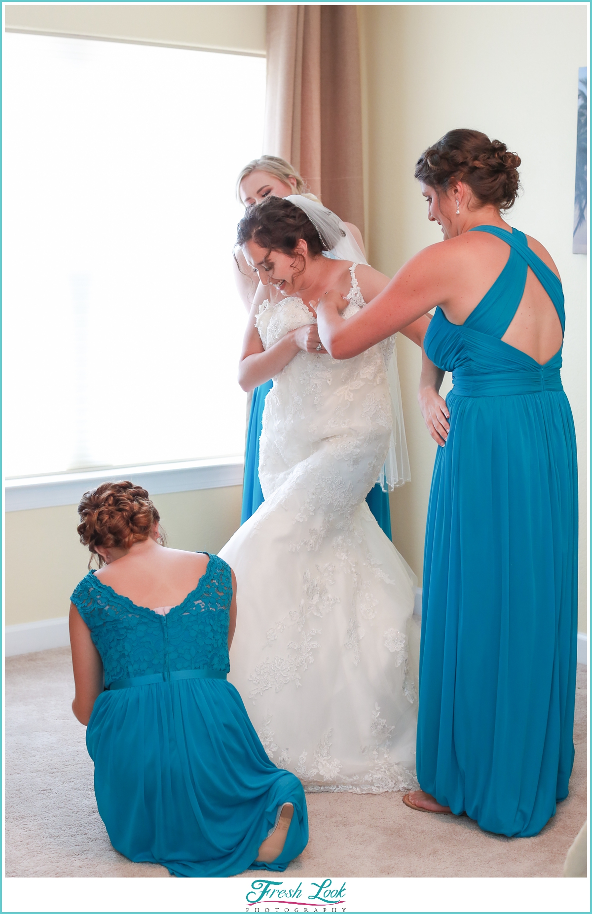 bridesmaids helping bride into dress